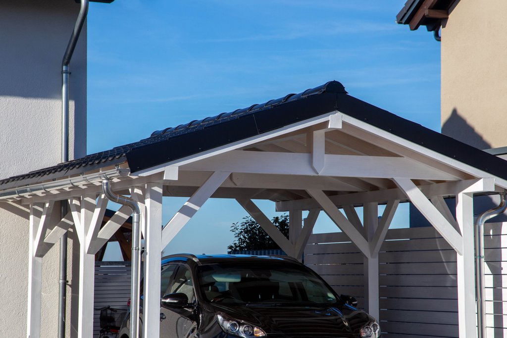 Ein weißes Holz-Carport und darunter ein Auto