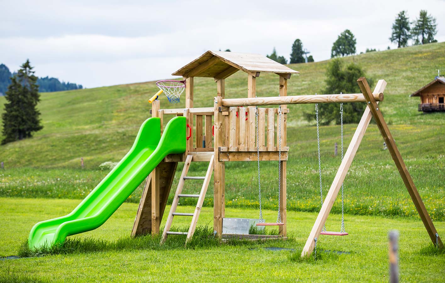 ein Spielturm mit Rutsche und Schaukel auf einer großen weiten Wiese