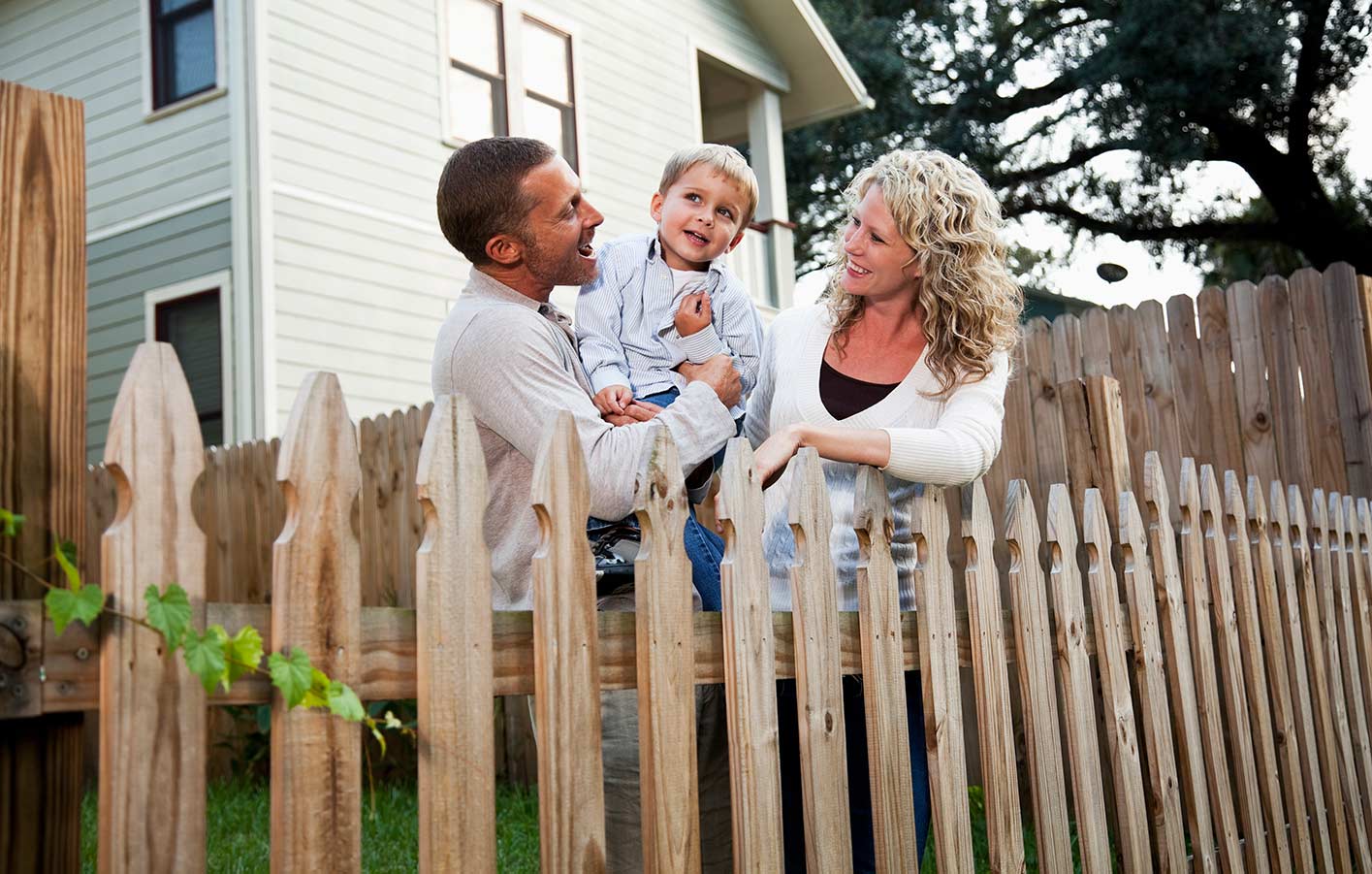 Familie mit Kind auf Ihrem Grundstück am Holzzaun